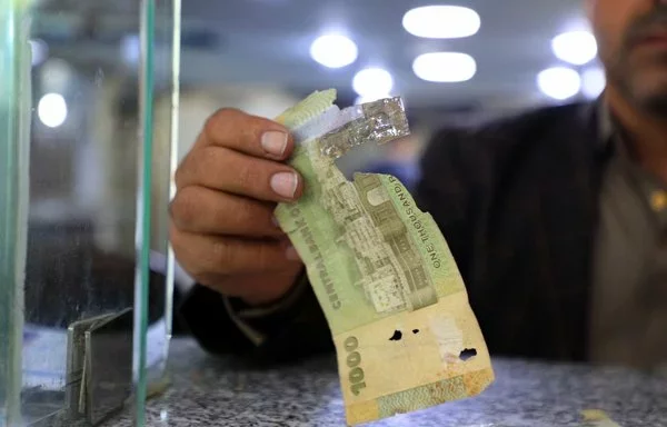 A man holds a torn Yemeni banknote at a currency exchange office in Sanaa on August 16, 2021. [Mohammed Huwais/AFP]