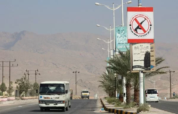 A sign prohibiting civilians from bearing firearms hangs in the former Al-Qaeda in the Arabian Peninsula (AQAP) bastion of al-Mukalla in Yemen's southern Hadramaut province, on November 30, 2018. [Saleh al-Obeidi/AFP]