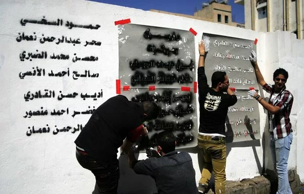 Yemeni graffiti artists paint a text on a wall in memory of the victims of an al-Qaeda attack during a March 2014 anti-terrorism campaign in Sanaa. [Mohammed Huwais/AFP]