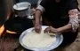 
An Egyptian woman prepares bread for her family in Zerzara village on the west bank of the Nile River, on February 26, 2022. [Khaled Desouki/AFP]        