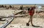 
A youth walks near water pumps drawing water from the Lake Assad reservoir, in the village of al-Tuwayhinah near the Tabqa Dam along the Euphrates river in al-Raqa province on July 27, 2021. [Delil Souleiman/AFP]        