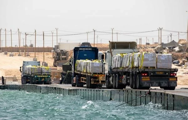 Trucks deliver aid to Gaza via the newly operational pier constructed by the US military. [CENTCOM]