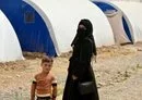 
A woman and child stand near tents at al-Jadaa camp in Iraq, which houses families repatriated from Syria's al-Hol camp, on April 29. Families undergo psychological rehabilitation at al-Jadaa. [Zaid al-Obeidi/AFP]        