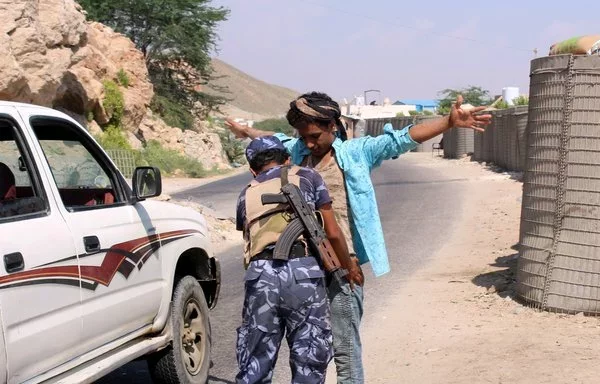 A member of the Yemeni security forces checks a man at a checkpoint in the former AQAP bastion of al-Mukalla in Yemen's Hadramaut province, on November 30, 2018. [Saleh al-Obeidi/AFP]