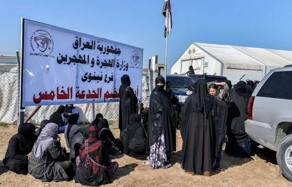 Iraqi women stand at the entrance to al-Jadaa camp near Mosul on March 10, after they were repatriated from Syria. [Raad Hashim X account]