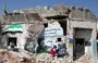
A mural being painted on a ruined house in the Syrian town of Binnish, in Idlib province, on August 25, 2023, denounces Russia's actions in Syria and Ukraine. [Omar Haj Kadour/AFP]        