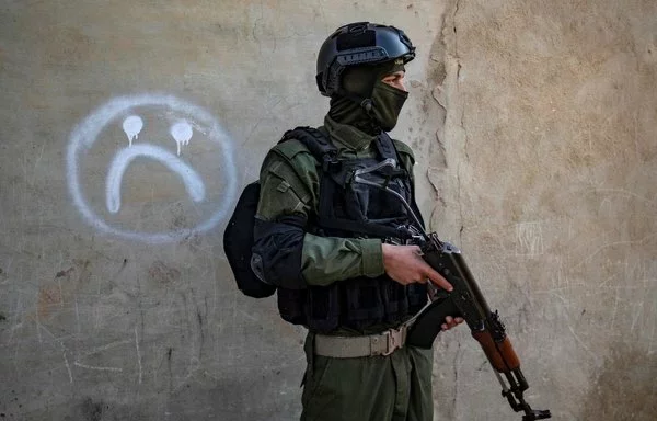 A member of the Syrian Kurdish internal security forces (Asayesh) walks past a house during a raid against suspected ISIS fighters in al-Raqa, the group's former 'capital' in Syria, on January 29, 2023. [Delil Souleiman/AFP]