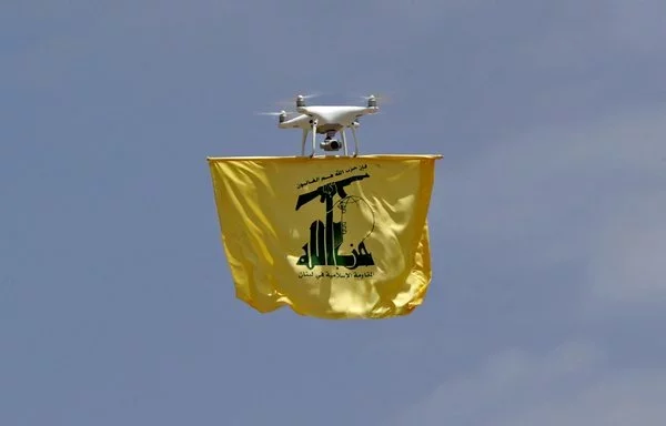 A drone carries a flag of Lebanese Hizbullah above Aaramta bordering Israel on May 21, 2023. [Anwar Amro/AFP]