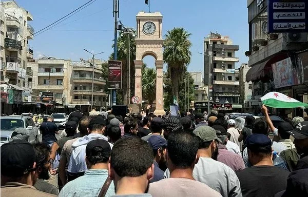 Anti-Tahrir al-Sham demonstrators throng al-Saa roundabout in Idlib city July 26. [Aleppo Fox]