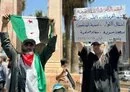 
A demonstrator in Idlib holds a sign denouncing Tahrir al-Sham's rule July 26. [Aleppo Fox]        