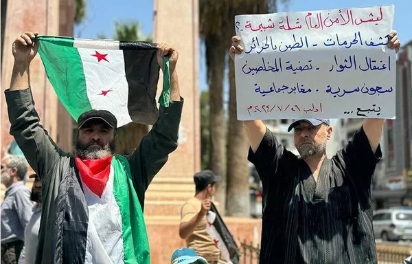 A demonstrator in Idlib holds a sign denouncing Tahrir al-Sham's rule July 26. [Aleppo Fox]