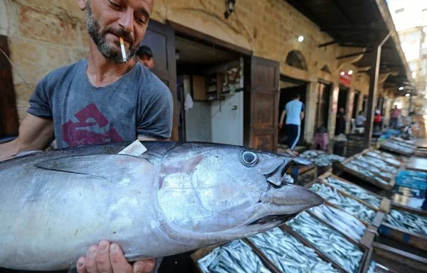 A vendor sells fish at a market in the Syrian city of Baniyas on July 25, 2022. The city's port and the area around it have become a closed military zone that not even fishermen may enter, local sources say. [Louai Beshara/AFP]