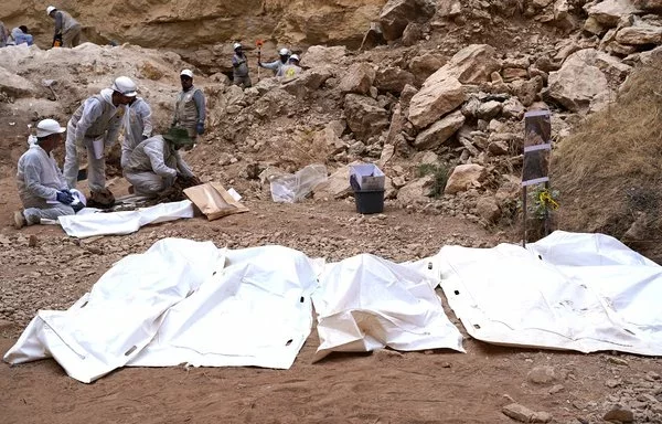 Experts retrieve the remains of ISIS victims from the Alo Antar hole in Tal Afar. [Zaid al-Obeidi/AFP]