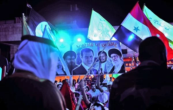 A banner showing Hizbullah chief Hassan Nasrallah, Syrian president Bashar al-Assad, Houthi leader Abdul Malik al-Houthi and Iranian leader Ali Khamenei is raised during a rally at al-Nayrab camp, east of Aleppo in May 2021. [AFP]