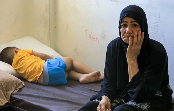 A child sleeps on a bed next to a relative on September 24, at a Beirut school that has been turned into a temporary shelter for families displaced by conflict from southern Lebanon. [AFP]