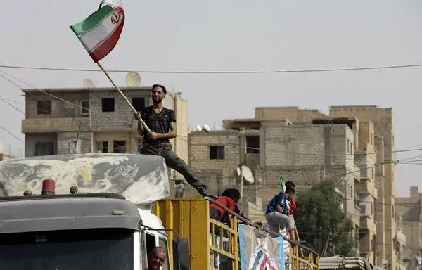 A Syrian man holds the Iranian flag atop a truck in the eastern city of Deir Ezzor on September 20, 2017. [Louai Beshara/AFP]