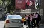 
Schoolgirls walk past a billboard praising Hizbullah in Damascus, Syria, on October 1. Human rights activists have accused the Lebanese party of operating sex trafficking rings. [Louai Beshara/AFP]        