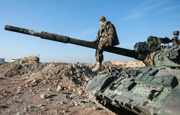 A militant poses for a picture after anti-regime fighters seized Syrian army military equipment and vehicles that were abandoned near Suran, on the highway to Damascus, on December 3. [Omar Haj Kadour/AFP]