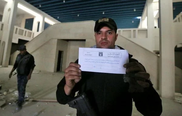 Iraqi forces examine an ISIS 'zakat' collection envelope found in Mosul's destroyed museum on March 13, 2017. [Ahmad al-Rubaye/AFP]