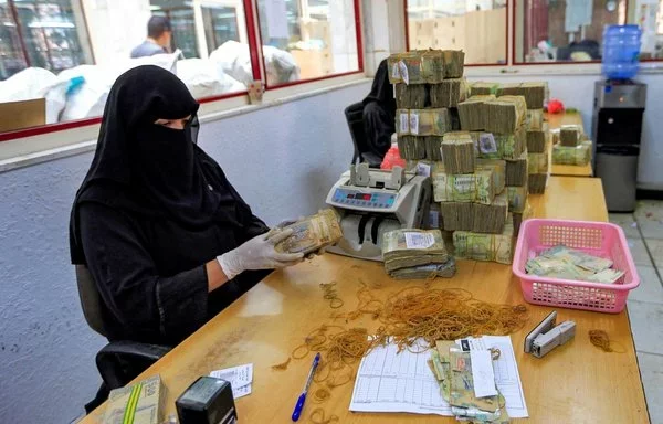 An employee counts currency at the central bank in Houthi-controlled Sanaa, June 23, 2021. [Mohammed Huwais/AFP]